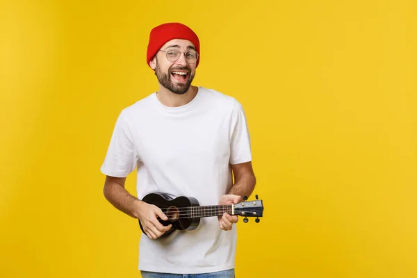 Close-up de jovem engraçado tocando uma guitarra. isolado em fundo de ouro amarelo — Fotografia de Stock