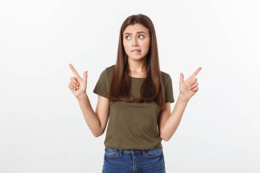 Gri arka planda yalnız duran mutlu ve şaşırmış genç bir bayan portresi. Kamera işaret ediyor.