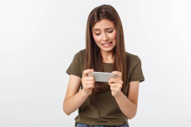 Mutlu, esmer ve neşeli bir kız akıllı telefondan video oyununda kazandı. Gri arka planda izole edildi.