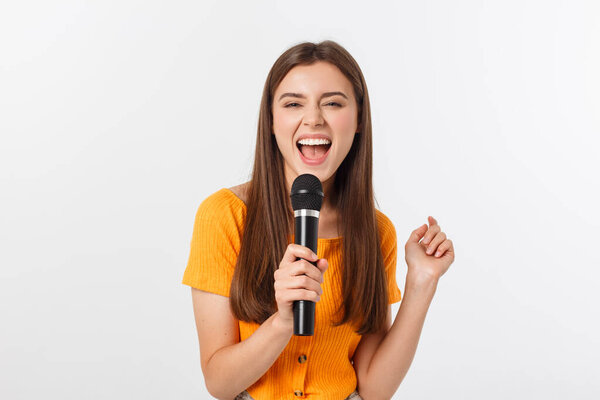 Young pretty woman happy and motivated, singing a song with a microphone, presenting an event or having a party, enjoy the moment