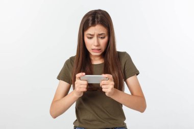 Mutlu, esmer ve neşeli bir kız akıllı telefondan video oyununda kazandı. Gri arka planda izole edildi.