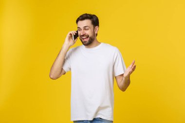 Sarı arka planda izole edilmiş genç bir adam telefonda konuşuyor.