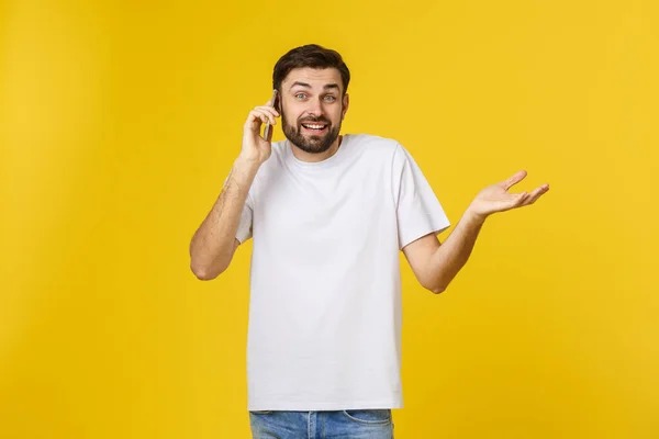 Retrato de um homem sério a falar ao telefone isolado num fundo amarelo. Olhando para a câmera — Fotografia de Stock