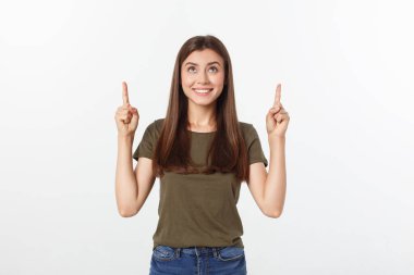 Gri arka planda yalnız duran mutlu ve şaşırmış genç bir bayan portresi. Kamera işaret ediyor.