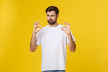 Sarı arka planda izole edilmiş iyi bir hareket gösteren neşeli genç bir adamın portresi.