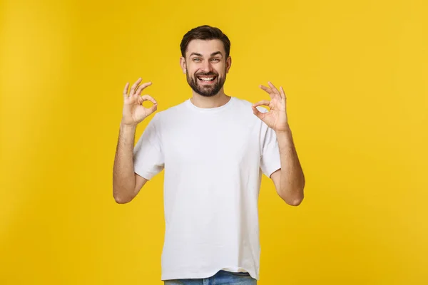 Портрет веселого молодого человека, показывающего нормальный жест, изолированный на желтом фоне — стоковое фото