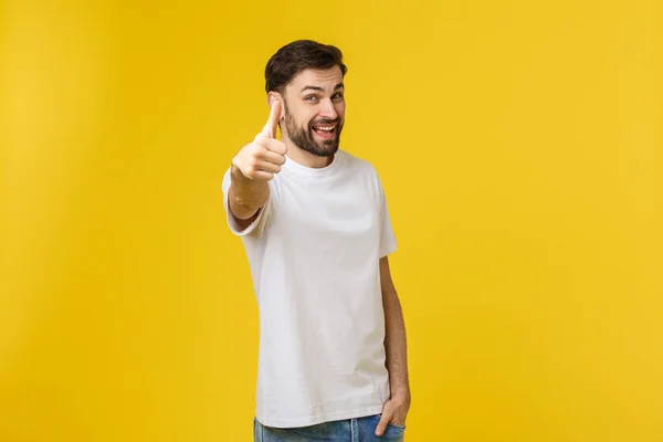 Jovem homem feliz com polegares para cima sinal em baixas isoladas no fundo amarelo — Fotografia de Stock