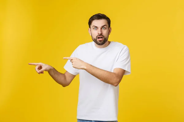 Jonge blanke man wijst naar iets interessants op een gele achtergrond — Stockfoto