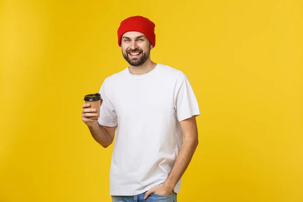 Man op geïsoleerde levendige gele kleur, een kopje koffie nemen in afhaalmaaltijden papier beker en glimlachend omdat hij zal begin de dag goed. — Stockfoto