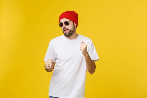 Retrato de um jovem bonito dançando e ouvindo música, isolado em fundo amarelo — Fotografia de Stock