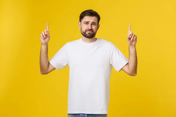Knappe man over geïsoleerde gele muur gefrustreerd en wijzend naar de voorkant. — Stockfoto