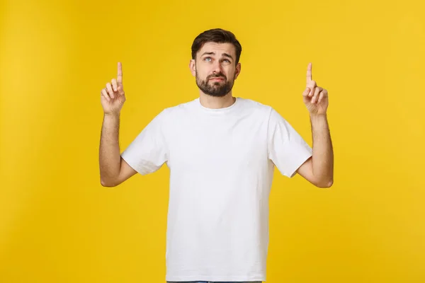 Bonito homem sobre a parede amarela isolada frustrado e apontando para a frente . — Fotografia de Stock