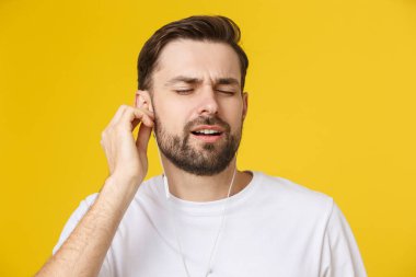 Sarı arka planda müzikten hoşlanan yakışıklı bir genç..