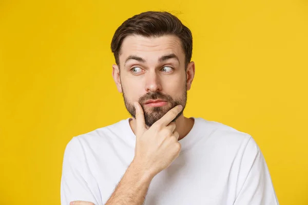 Pensando homem isolado no fundo amarelo. Retrato de close-up de um homem casual jovem e pensativo olhando para o copyspace. Modelo masculino caucasiano . — Fotografia de Stock