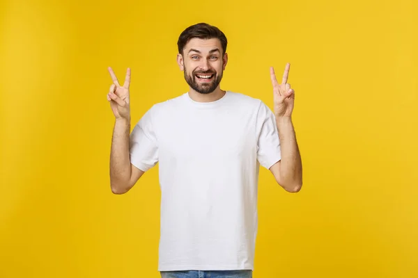 Joven hombre guapo con camiseta a rayas sobre fondo amarillo aislado sonriendo mirando a la cámara mostrando los dedos haciendo señal de victoria. Número dos. — Foto de Stock