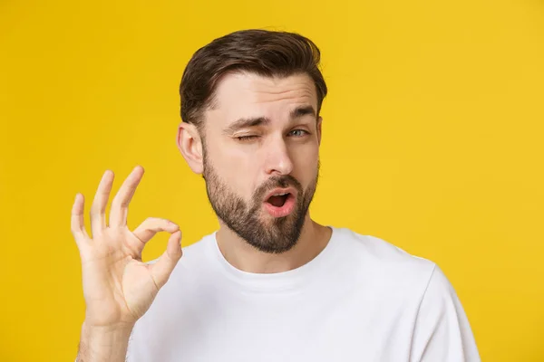Satisfied young man showing okay sign isolated on yellow background. — Stock Photo, Image