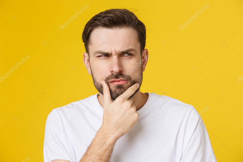 Thinking man isolated on yellow background. Closeup portrait of a casual young pensive man looking up at copyspace. Caucasian male model.