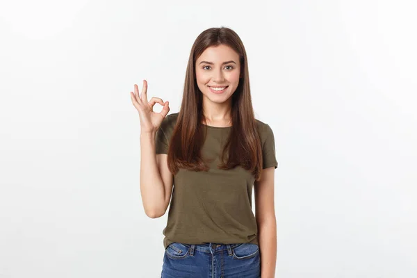 Szczęśliwa młoda kobieta pokazuje ok znak palcami, mrugając na białym tle na szarym tle. — Zdjęcie stockowe