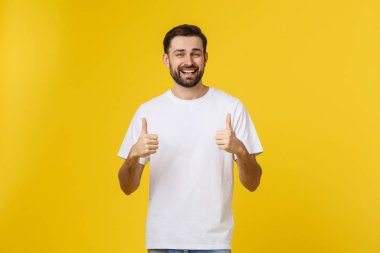 Sarı arka planda izole edilmiş gündelik kıyafetleri olan mutlu genç bir adam.