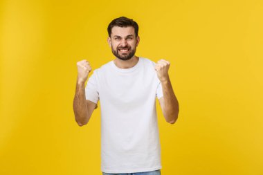 Kolları havada mutlu genç bir adam sarı bir arka planda izole edilmiş..