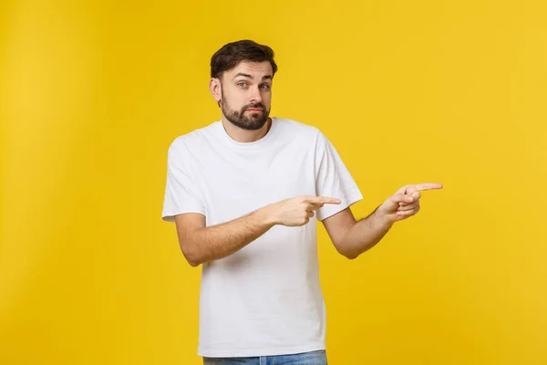 Knappe man over geïsoleerde gele muur gefrustreerd en wijzend naar de voorkant. — Stockfoto