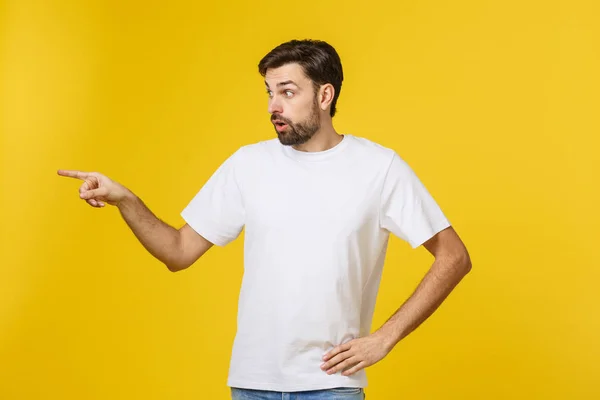 Knappe man over geïsoleerde gele muur gefrustreerd en wijzend naar de voorkant. — Stockfoto