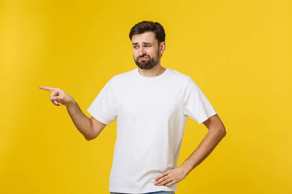 Beau homme sur un mur jaune isolé frustré et pointant vers l'avant . — Photo