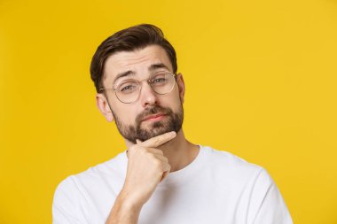 Düşünen adam sarı arka planda izole edilmiş. Telif uzayına bakan genç ve düşünceli bir adamın yakın plan portresi. Beyaz erkek model..