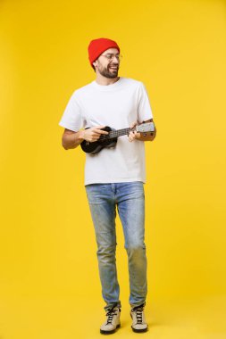 Gitarist adam elektro gitaristle çalar. Parlak duygularla, sarı arka planda izole edilmiş..