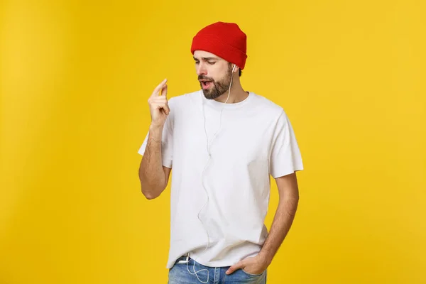 Porträtt av en vacker ung man dans och lyssna musik, isolerad på gul bakgrund — Stockfoto