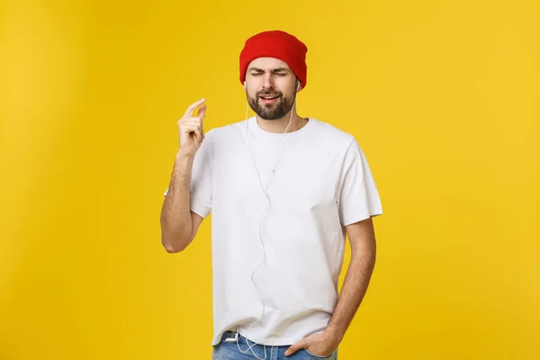 Retrato de um jovem bonito dançando e ouvindo música, isolado em fundo amarelo — Fotografia de Stock