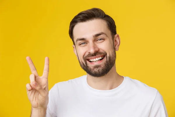 Homem bonito jovem vestindo camiseta listrada sobre fundo amarelo isolado sorrindo olhando para a câmera mostrando os dedos fazendo sinal de vitória. Número dois. — Fotografia de Stock