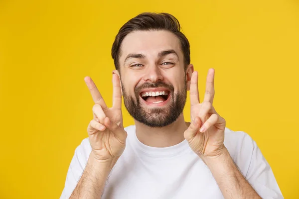 Young handsome man wearing striped t-shirt over isolated yellow background smiling looking to the camera showing fingers doing victory sign. Number two — Stock Photo, Image