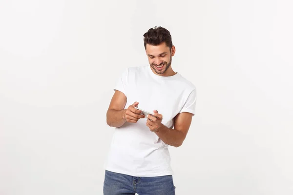 Portret van een jonge man spelen videospelletjes op mobiele telefoon op grijze achtergrond. — Stockfoto