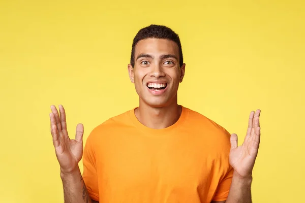 Homem caucasiano atraente, animado em t-shirt mostrando caixa ou algo grande, mãos abertas perto do peito para formar grande objeto, explicar algo, discutir vastas vendas, ter diálogo, fundo amarelo — Fotografia de Stock