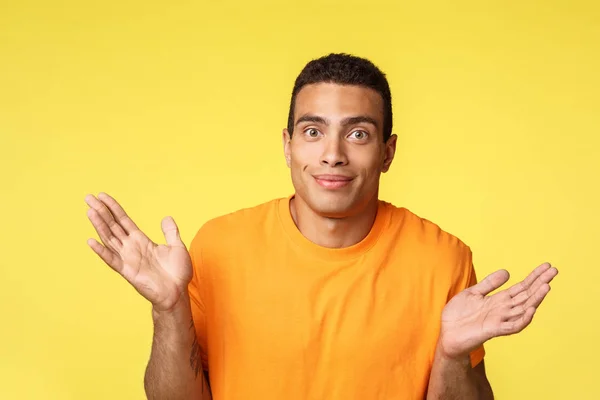 Le gars s'excuse, ne peut pas aider, n'a rien à offrir. Maladroit mignon homme caucasien masculin écarté les mains latéralement, haussant les épaules et souriant comme ne peut pas dire, réponse perplexe, fond jaune — Photo