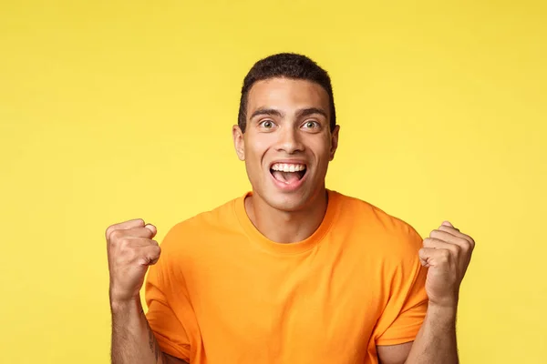 Réalisation, célébration et concept gagnant. Beau soulagé joyeux jeune homme serrer les mains, poing pompe et sourire devenir gagnant ou champion, recevoir le prix, atteindre le succès, fond jaune — Photo