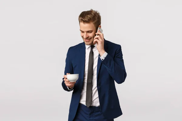 Büro-, Unternehmens- und Geschäftskonzept. selbstbewusster, gut aussehender, eleganter männlicher Unternehmer, der mit Partnern telefoniert, Smartphone in der Hand hält, Freund anruft, Kaffee trinkt — Stockfoto