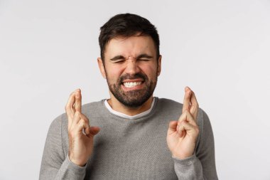 Neşeli, umutlu, umut dolu, iyimser ve baştan çıkarıcı bir adam, şans dileyin, gözlerinizi kapatın ve gülümseyin, kazanmayı çok isteyin, umut edin, iyi haberleri bekleyin, beyaz arka planda durun