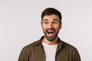 Bu çok komik. Eğlenmiş ve merak etmiş, ceketli çekici sakallı yetişkin erkek, sola bak ve komik olaya gül, şaşırmış bir şekilde gülümse, ilginç bir partiye katıl, beyaz arka planda dur.