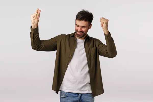 Good-looking lucky and successful young man achieve goal, raise hands up and dancing joyfully, fist pump triumphing, smiling cheerful, feeling happy achieve goal, excited celebrate victory — Stock Photo, Image