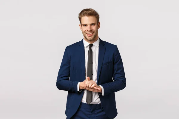 Guapo y seguro, empresario masculino inteligente en traje clásico, frotando las palmas y sonriendo complacido, anticipar hacer dinero grande, buen negocio, saborear algo bueno, de pie fondo blanco — Foto de Stock