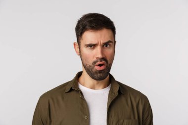 Bekle bir saniye. Şaşırmış ve telaşlı, endişeli sakallı genç adam biraz endişeli ve hayal kırıklığına uğramış görünüyor, garip bir şey duyuyor, suratını ekşiten, şüpheli ve şüpheli bakan, beyaz arka plan