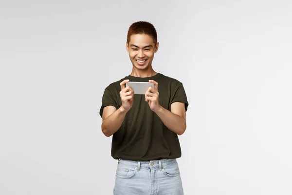 Opgewonden jonge man spelen spel op zijn smartphone geïsoleerd over witte achtergrond — Stockfoto