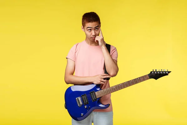 Bello giovane musicista che suona la chitarra e canta, isolato su sfondo giallo — Foto Stock