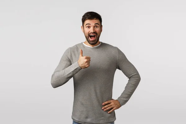 Wonderful idea, lets do it. Excited, cheerful, supportive bearded adult man in grey sweater, give positive feedback, adore something really good, show thumb-up approval, like or enthusiastic gesture — Stock Photo, Image