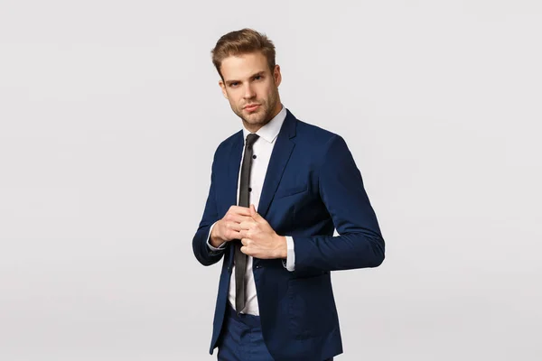 Determined, confident businessman in suit, fixing jacket, looking sassy and pleased camera, signed good deal, feeling lucky and self-assured, manage business, standing white background — Stock Photo, Image