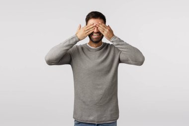 Peekabo, kim var orada. Neşeli ve şakacı sakallı genç baba bebek saklambaç oynuyor, kapalı gözler, gözleri bağlı ve gülümsüyor mutlu, beyaz arka planda bekliyor sürpriz