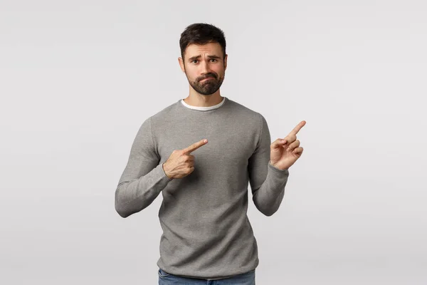 Guy trying say bad news, pointing upper right corner with regret and disappointment. Handsome bearded husband indicating promo upset and skeptical, smirk look distressed or unsatisfied — Stock Photo, Image