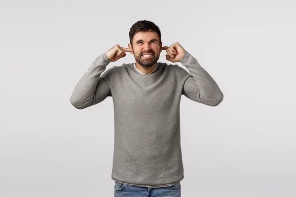 Angry, irritated and displeased male freelancer working home being interrupted loud neighbour, repairment works noise, shut ears grimacing and cursing in mind, look up hateful, white background — Stock Photo, Image